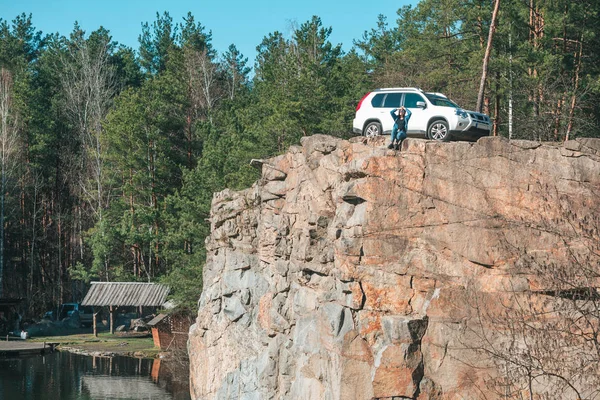 Mujer relajante de pie en el borde del acantilado cerca del lago. coche todoterreno . — Foto de Stock