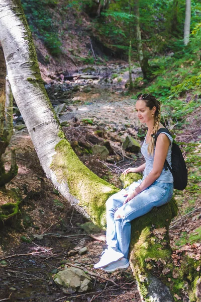 Donna seduta nessun albero nella foresta. sole splende sul viso — Foto Stock