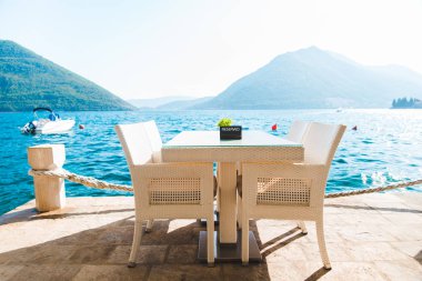 güzel bir deniz ve dağ manzarası ile sahilde Cafe tablo. üzerinde ayrılmış plaka