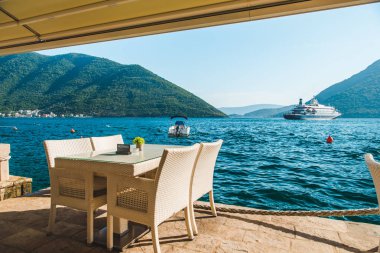 güzel bir deniz ve dağ manzarası ile sahilde Cafe tablo. üzerinde ayrılmış plaka. Cruise liner arka plan üzerinde