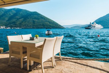 güzel bir deniz ve dağ manzarası ile sahilde Cafe tablo. üzerinde ayrılmış plaka