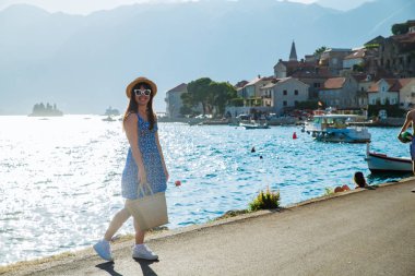 City quay tarafından yürüyen genç oldukça stil sahibi kadın. Deniz ve dağlar arka plan üzerinde