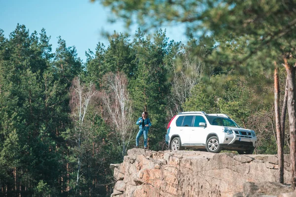 Mladá stylová žena na útesu s bílým SUV autem — Stock fotografie