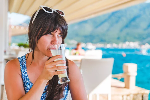바다에서 비치 카페에 앉아있는 동안 주스를 마시는 여자 — 스톡 사진