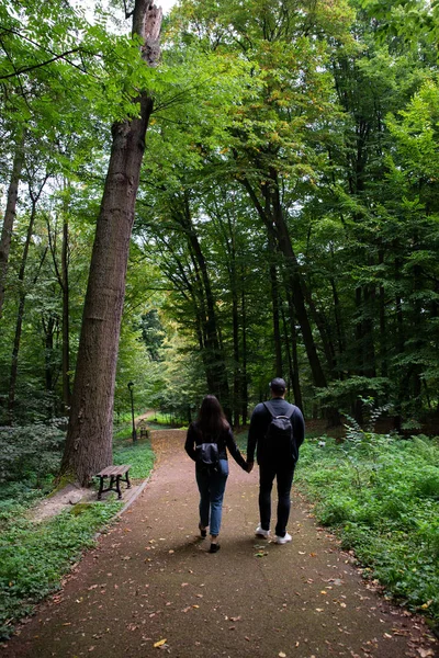 Fiatal pár sétál a városi park mellett kéz a kézben — Stock Fotó