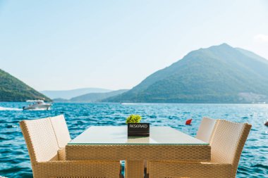 güzel bir deniz ve dağ manzarası ile sahilde Cafe tablo. üzerinde ayrılmış plaka