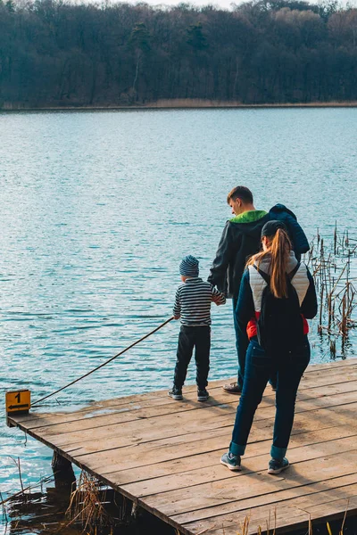 Père et mère avec garçon enfant jouer avec banc près de l'eau — Photo