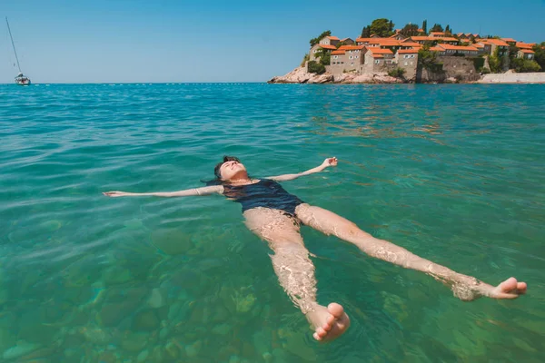 Genç güzel kadın mavi denizde yüzme. Sveti stefan plaj — Stok fotoğraf