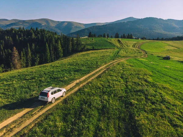 Voiture blanche SUV dans les montagnes au sentier sentier sur le coucher du soleil — Photo