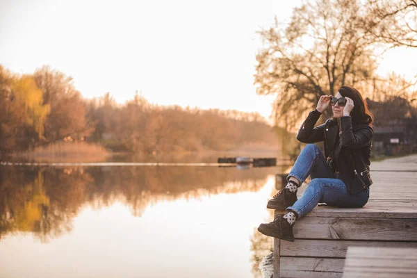 Tineri destul de moda femeie așezat pe dig pe apus de soare cu vedere frumoasă la râu — Fotografie, imagine de stoc