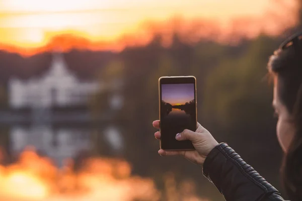 Vrouw het nemen van foto van zonsondergang op haar telefoon — Stockfoto