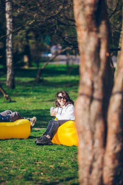 Par om på gul uppblåsbar madrass i City Park. Läs bok. dricka smoothies — Stockfoto