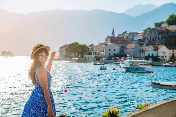 Giovane bella donna alla moda a piedi dalla banchina della città. mare e montagne sullo sfondo — Foto Stock