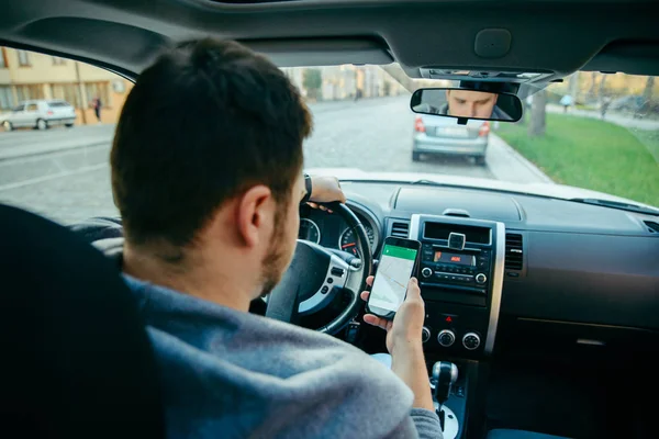 Muž ruce na volant při použití telefonu jako navigátor — Stock fotografie