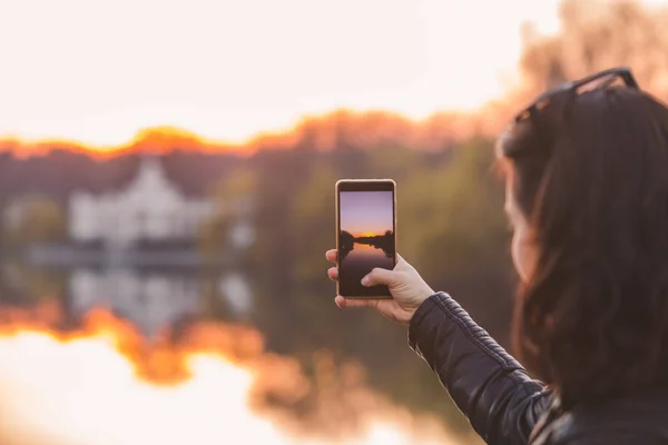 Woman taking picture of sunset on her phone — Stock Photo, Image