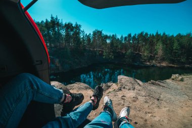 arka planda araba gövde gölde oturan çift. spor ayakkabı ve kot bacaklar