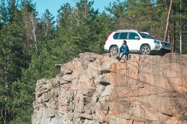 Donna seduta sulla scogliera con bella vista nella giornata di sole. suv auto sullo sfondo — Foto Stock