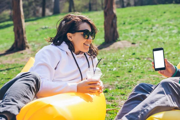 Couple laying on inflatable mattress in city park at sunny day. talking and chatting — Stock Photo, Image