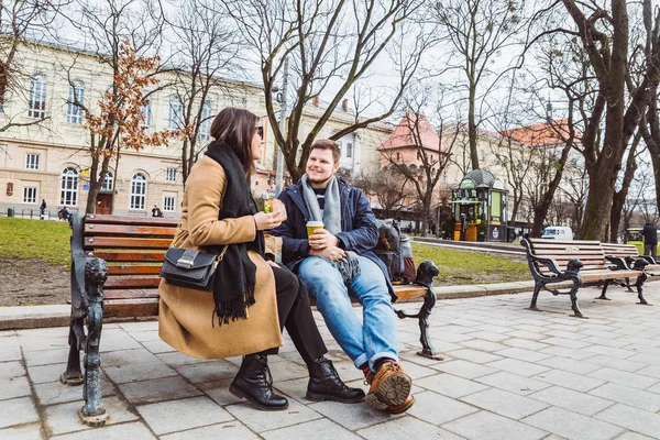 Pareja de adultos jóvenes comiendo comida rápida en el banco del parque de la ciudad — Foto de Stock