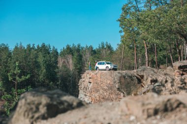 ormanda kayalık uçurumun kenarında oturan adam.