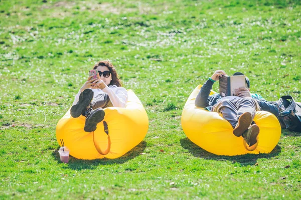 Pareja que pone en el parque de la ciudad en el colchón inflable amarillo — Foto de Stock