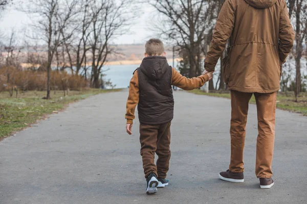 Pai com filho andando pelo parque de mãos dadas — Fotografia de Stock