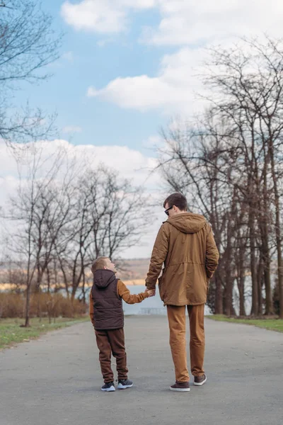 Padre con hijo caminando por el parque tomados de la mano —  Fotos de Stock