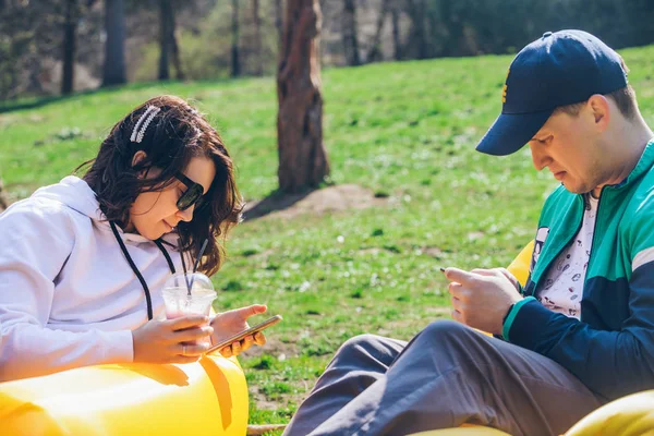 Casal que põe no colchão inflável no parque da cidade no dia ensolarado. falar e conversar — Fotografia de Stock