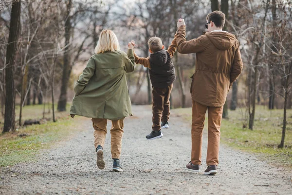 Joven hermosa familia caminando cogido de la mano por el parque de la ciudad —  Fotos de Stock