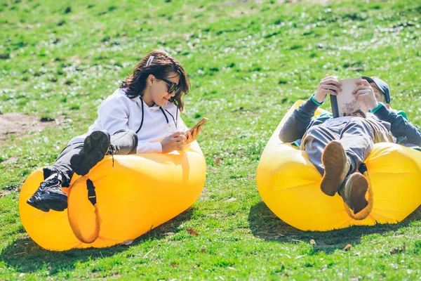 Pareja que pone en el parque de la ciudad en el colchón inflable amarillo — Foto de Stock