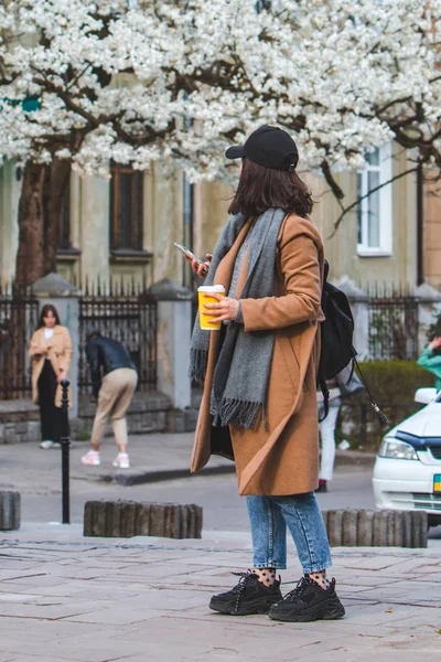 Mujer joven y elegante caminando por la calle con taza de café —  Fotos de Stock