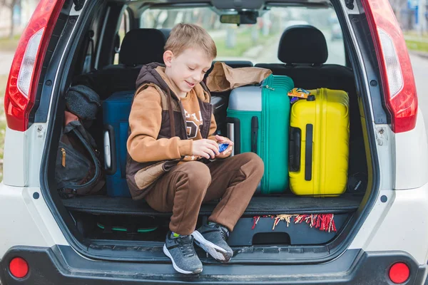 little kid looking into paper bag with candies sitting in car trunk