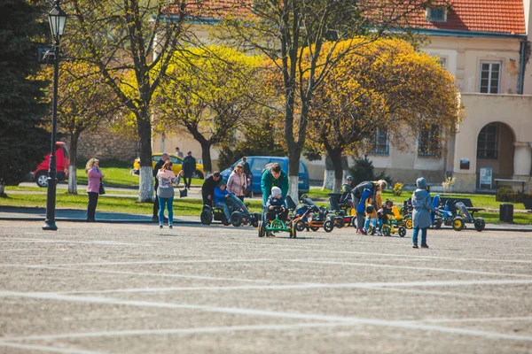 ZHOVKVA, UCRANIA - 14 de abril de 2019: niños montando coches a pedal por plaza de la ciudad — Foto de Stock