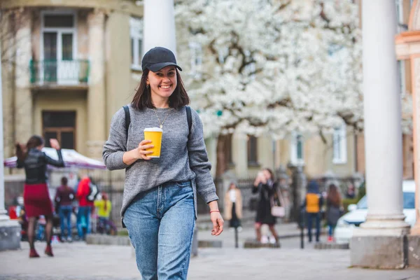 Jovem mulher elegante andando pela rua com xícara de café — Fotografia de Stock