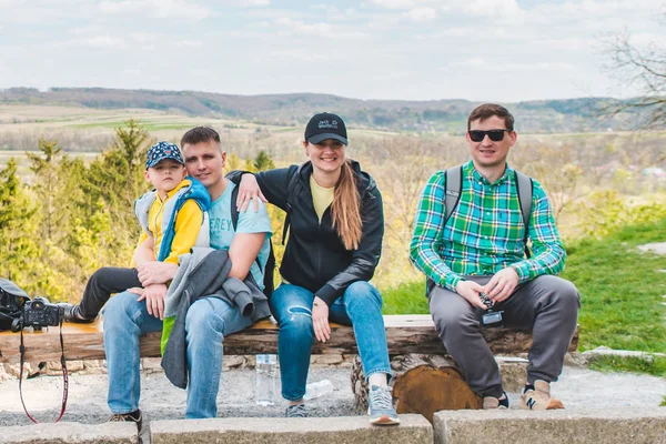 Група друзів з дітьми, що сидять на дерев'яній лавці з красивим видом — стокове фото