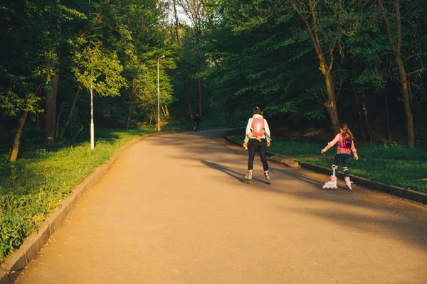 LVIV, UCRAINA - 27 aprile 2018: madre con figlia che pattina vicino al parco cittadino estivo al tramonto — Foto Stock