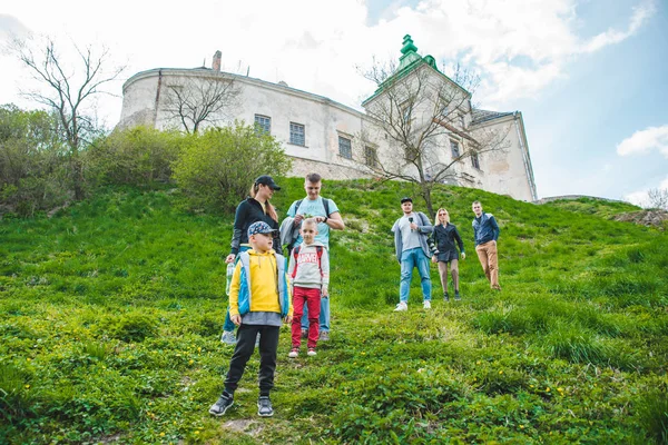 OLESKO, UCRAINA - 20 aprile 2019: felice gruppo di adulti con bambini che passeggiano vicino al vecchio castello — Foto Stock