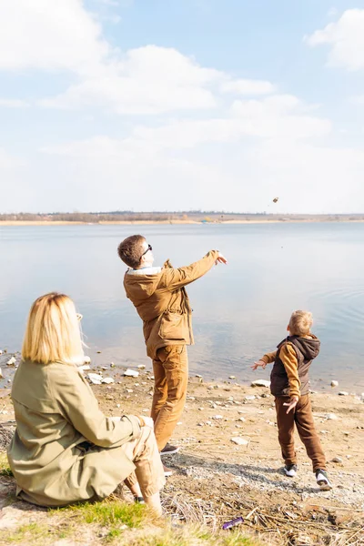 Padre enseñando poco hijo tirar piedras en el agua — Foto de Stock