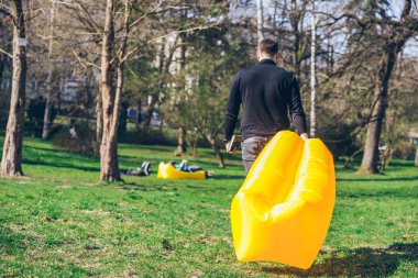 kitap okumak için yere sarı şişme yatak ile yürüyen adam