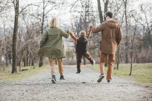 Joven hermosa familia caminando cogido de la mano por el parque de la ciudad —  Fotos de Stock