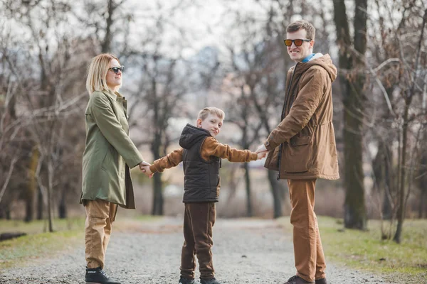 Joven hermosa familia caminando cogido de la mano por el parque de la ciudad —  Fotos de Stock