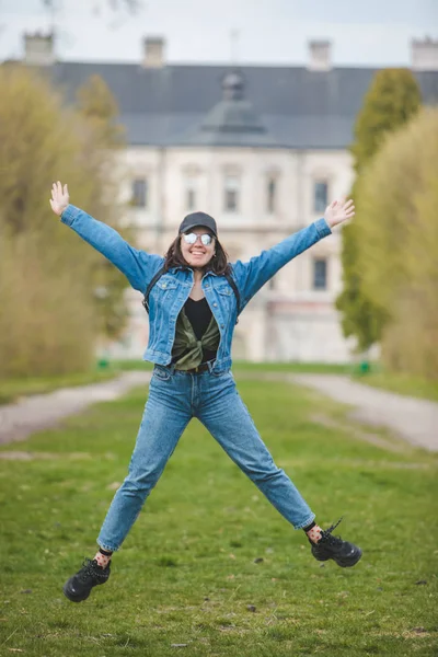 Улыбающаяся женщина, прыгающая перед старым замком — стоковое фото