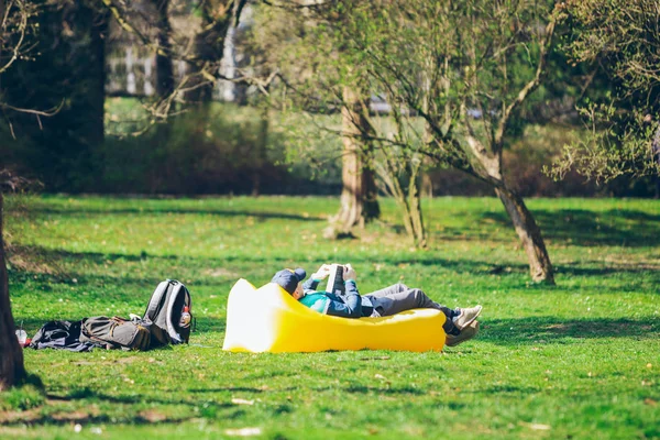 Concepto de lectura de libros. hombre en parque de la ciudad en colchón inflable — Foto de Stock