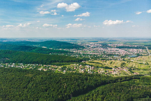 Aerial view of the city in the center of green forest. blue sky with white clouds