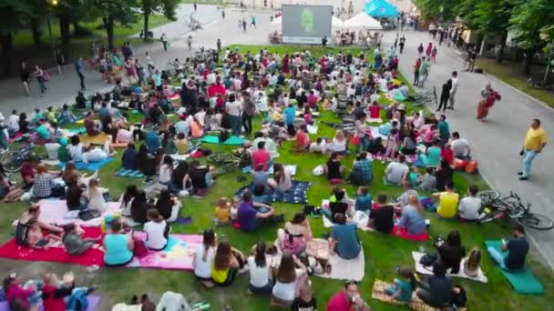 Ludzie zebrani w parku miejskim, aby obejrzeć film w kinie na otwartym powietrzu. — Wideo stockowe