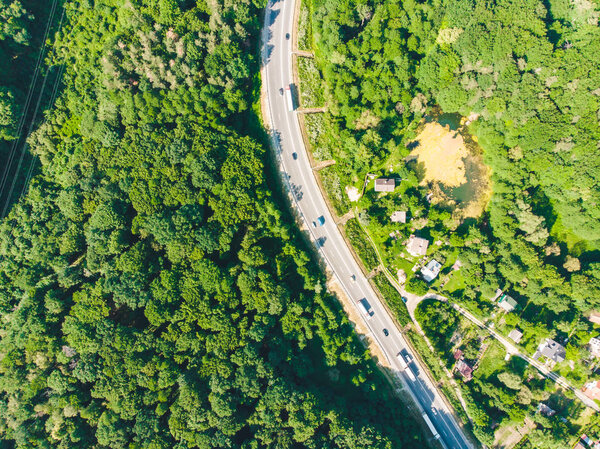 Overhead view of highway near village. forest around