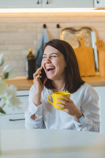 Woman drinking tea from yellow mug at the kitchen — Stock Photo, Image