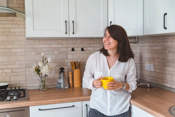 Jovem mulher muito elegante segurando caneca amarela na cozinha branca — Fotografia de Stock