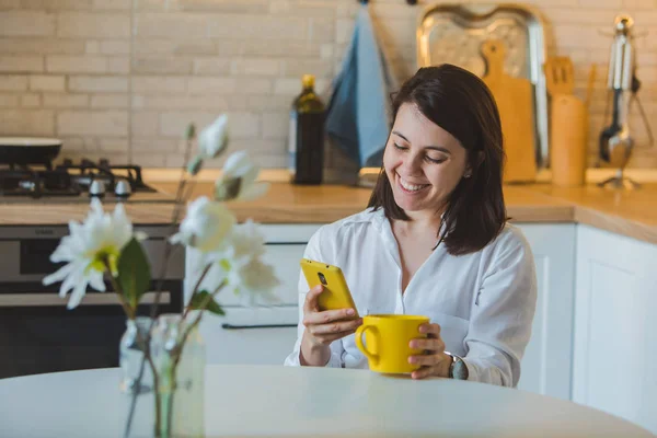 Woman drinking tea from yellow mug at the kitchen — Stock Photo, Image