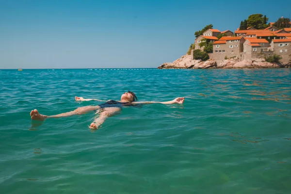 Ung vacker kvinna bada i blå havet. Sveti stefan strand — Stockfoto